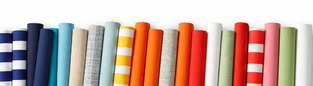 Commercial umbrella fabric rolls in assorted colors and patterns for custom outdoor branding, showcasing durable acrylic materials used in hospitality and resort environments.